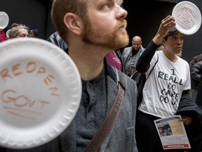 A furloughed government worker affected by the shutdown wears a shirt that reads "I Really Do Care Do U?" during a silent protest against the ongoing partial government shutdown on Capitol Hill in Washington, Wednesday, Jan. 23, 2019. Protesters held up disposable plates instead of posters to avoid being arrested.