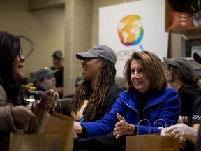 House Speaker Nancy Pelosi of Calif., center, smiles as she helps give out food at World Central Kitchen, the not-for-profit organization started by Chef Jose Andres, Tuesday, Jan. 22, 2019, in Washington. The organization devoted to providing meals in the wake of natural disasters, has set up a distribution center just blocks from the U.S. Capitol building to assist those affected by the government shutdown.