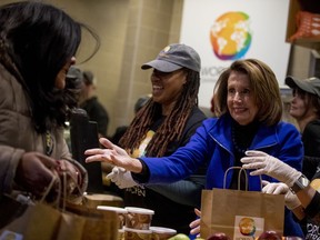 House Speaker Nancy Pelosi of Calif., center, smiles as she helps give out food at World Central Kitchen, the not-for-profit organization started by Chef Jose Andres, Tuesday, Jan. 22, 2019, in Washington. The organization devoted to providing meals in the wake of natural disasters, has set up a distribution center just blocks from the U.S. Capitol building to assist those affected by the government shutdown.