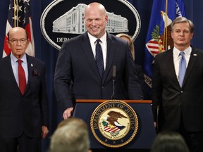 Acting Attorney General Matt Whitaker, center, smiles at a question from a reporter after an announcement of an indictment of Chinese telecommunications companies including Huawei, on violations including bank and wire fraud, Monday, Jan. 28, 2019, at the Justice Department in Washington. At left is Commerce Secretary Wilbur Ross, and FBI Director Christopher Wray, at right.