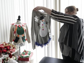 Doris Cochran holds "an ugly sweater," which she is planning to sell, Friday, Jan. 18, 2019 in her apartment in Arlington, Va., Cochran is a disabled mother of two young boys living in subsidized housing in Arlington, Virginia. She's stockpiling canned foods to try to make sure her family won't go hungry if her food stamps run out. She says she just doesn't know "what's going to happen" and that's what scares her the most.