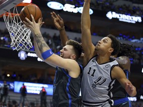 Dallas Mavericks forward Luka Doncic (77) pulls down a rebound against San Antonio Spurs guard Bryn Forbes (11) in the first half of an NBA basketball game, Wednesday, Jan. 16, 2019, in Dallas.