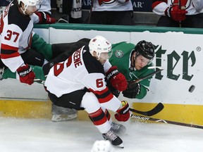 Dallas Stars center Radek Faksa (12) is knocked off his feet by New Jersey Devils center Pavel Zacha (37) and defenseman Andy Greene (6) during the first period of an NHL hockey game in Dallas, Wednesday, Jan. 2, 2019.