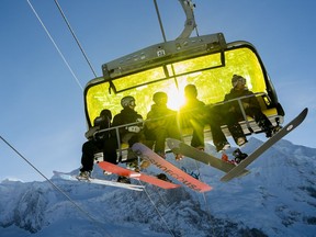 Skiers sit in a chairlift during a sunny winter day in front of the Jungfraujoch, in Wengen, Switzerland, Tuesday, Jan. 15, 2019.