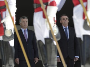 Brazil's President Jair Bolsonaro, right, and the Argentina's President Mauricio Macri, listens to the national anthem of Argentina during a welcome ceremony, at the Planalto presidential palace, in Brasilia, Brazil, Wednesday, Jan. 16, 2019. Macri is on a one-day visit to Brazil.