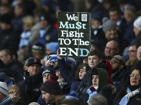 A supporter holds a poster before the English Premier League soccer match between Manchester City and Liverpool at the Etihad Stadium in Manchester, England, Thursday, Jan. 3, 2019.