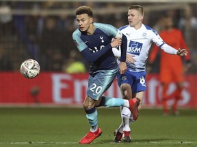Tottenham's Dele Alli, left, and Tranmere Rovers' Jay Harris challenge for the ball during the English FA Cup third round soccer match between Tranmere Rovers and Tottenham Hotspur at Prenton Park stadium in Birkenhead, England, Friday, Jan. 4, 2019.