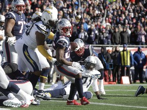 New England Patriots running back Sony Michel (26) scores a touchdown in front of Los Angeles Chargers defensive tackle Darius Philon (93) during the first half of an NFL divisional playoff football game, Sunday, Jan. 13, 2019, in Foxborough, Mass.