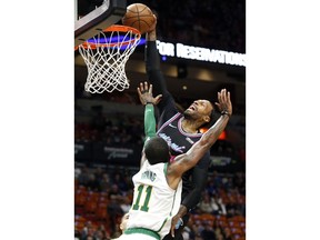 Miami Heat forward James Johnson, top, goes to the basket against Boston Celtics guard Kyrie Irving (11) during the first half of an NBA basketball game, Thursday, Jan. 10, 2019, in Miami.