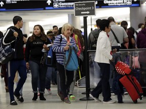 Passengers wait in line at a security checkpoint at Miami International Airport, Friday, Jan. 18, 2019, in Miami. The three-day holiday weekend is likely to bring bigger airport crowds.