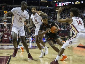 Miami guard Anthony Lawrence ll drives between Florida State center Christ Koumadje (21), forward Phil Cofer (0) and guard Terrance Mann in the first half of an NCAA college basketball game in Tallahassee, Fla., Wednesday, Jan. 9, 2019.