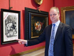 In this photo made available on Jan. 1, 2019 by the Uffizi gallery press office, Eike Schmidt, director of the Uffizi Gallery, poses for a photo as he points to a copy of a still-life "Vase of Flowers", by Dutch artist Jan van Huysum, with writing in red reading "stolen", inside the Uffizi gallery, in Florence, Italy. Schmidt is urging Germany to return the Dutch masterpiece stolen by the Nazi troops during World War II, which is in the hands of a German family who hasn't returned it despite numerous appeals. (Uffizi Gallery press office via AP)