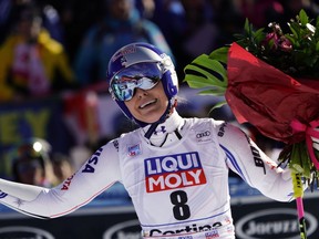 FILE - In this Sunday, Jan. 20, 2019 filer, United States' Lindsey Vonn holds a bunch of flowers after completing an alpine ski, women's World Cup super-G in Cortina D'Ampezzo, Italy. It seemed like destiny played a role on Sunday when Mikaela Shiffrin won what could very well turn out to be Lindsey Vonn's last race. Vonn broke down emotionally after she failed to finish a World Cup super-G on knees so worn down that she describes them as "bone on bone." Shiffrin then came down nine racers later and won her first speed race at the premier stop on the women's circuit.
