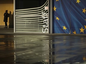 A woman smokes outside the European Commission headquarters in Brussels, Monday, Jan. 14, 2019. In a letter to Britain's Prime Minister Theresa May published Monday, European Council President Donald Tusk and European Commission President Jean-Claude Juncker offered an assurance that the backstop "would only be in place for as long as strictly necessary".