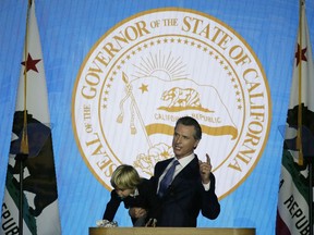 In this Monday, Jan. 7, 2019, photo, California Gov. Gavin Newsom holds his son Dutch while giving his address at his inauguration in Sacramento, Calif. Newsom gets his chance this week to show how he'll resolve a central tension in his platform: advancing expensive new programs while maintaining robust savings.