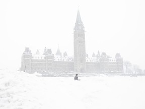 A pedestrian walks past a snowbank on Parliament Hill in Ottawa on Sunday, January 20, 2019. A powerful winter storm that brought heavy rain and snow to much of Eastern and Central Canada has closed schools, flooded streets, knocked out power and is forcing school buses to stay off the roads in Toronto today as temperatures plummet.