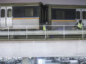 Metropolitan Atlanta Rapid Transit Authority (MARTA) employees inspect an out-of-service train that got stuck on the tracks just north of Hartsfield-Jackson International Airport, Wednesday, Jan. 16, 2019, in Atlanta. Rail Operations Chief Dave Springstead says normal service to the airport may not resume until Thursday because officials need to bring in a crane to lift the train.