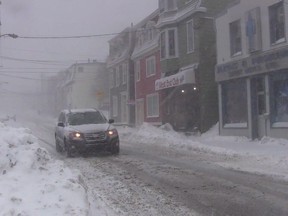 A car drives downs a snow-covered street in St. John's on Wednesday, Jan. 2, 2019. Disgruntled St. John's residents took to the streets early Wednesday afternoon to shovel away snow from a powerful storm, just before a second round of intense wind and snowfall began battering Newfoundland and Labrador. Travel to Newfoundland by air and sea was being disrupted after a winter storm dumped between 30 and 40 centimetres of snow in parts of the province.