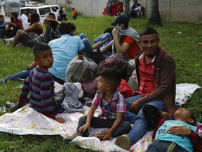 Freddy Rivas, second right, of Tocoa, Honduras, sits with his sons Josue, left, and Elkin, center, and his brother Mario, as they wait with scores of other migrants hoping to join a caravan to travel to the U.S. border, in San Pedro Sula, Honduras, Monday, Jan. 14, 2019. Hundreds of Hondurans hoping to reach the U.S. began gathering at a main bus station in San Pedro Sula Monday night to join a caravan that had been advertised in social media as departing in the early hours of Tuesday morning.