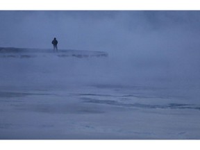 A man walks along the shore of Lake Michigan, Wednesday, Jan. 30, 2019, in Chicago. A deadly arctic deep freeze enveloped the Midwest with record-breaking temperatures on Wednesday, triggering widespread closures of schools and businesses, and prompting the U.S. Postal Service to take the rare step of suspending mail delivery to a wide swath of the region.