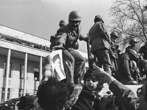 FILE - In this Jan. 15, 1979 file photo, a smiling Iranian soldier is hailed by demonstrators who decorated them with flowers and pictures of Ayatollah Ruhollah Khomeini, in Tehran, Iran. Wednesday, Jan. 16, 2019 marks the 40th anniversary of the shah abandoning his Peacock Throne and leaving his nation for the last time in his life, setting the stage for the country's 1979 Islamic Revolution only a month later.