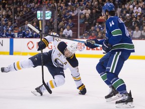 Vancouver Canucks defenseman Erik Gudbranson (44) fights for control of the puck with Buffalo Sabres right wing Kyle Okposo (21) during first period NHL action at Rogers Arena in Vancouver, Friday, Jan 18, 2019.