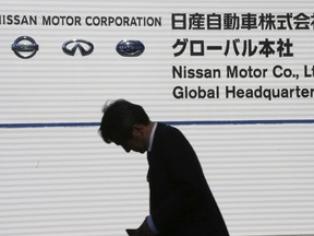 A man walks past the corporate logos at the global headquarters of Nissan Motor Co., Ltd. in Yokohama Wednesday, Jan. 9, 2019. Nissan is showing the beefed up version of its hit Leaf electric car as the Japanese automaker seeks to distance itself from the arrest of its star executive Carlos Ghosn.