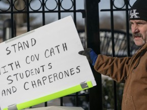 A man places a sign showing support for the students of Covington Catholic Catholic High School in front of the Catholic Diocese of Covington in Covington, Ky., Tuesday, Jan 22, 2019.