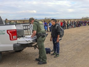 This Monday, Jan. 14, 2019 photo released by U.S. Customs and Border Protection shows some of 376 Central Americans the Border Patrol says it arrested in southwest Arizona, the vast majority of them families, who used short holes dug under a barrier to cross the border in multiple spots about 10 miles east of San Luis, Ariz. The unusually large group was almost entirely from Guatemala.