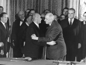 FILE - In this Jan. 22, 1963 file photo, German Chancellor Konrad Adenauer, centre left, hugs France President Charles de Gaulle after signing the Elysee friendship treaty in the Elysee palace in Paris, France. The leaders of France and Germany are poised to sign the Aachen accord Tuesday Jan. 22, 2019, renewing their friendship and pledging greater cooperation, exactly 56-years after their predecessors inked the Elysee Treaty that set the tone for the two countries' future relations. (AP Photo/File)