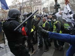 FILE - In this Saturday, Dec. 8, 2018 file photo, police officers clash with demonstrators wearing yellow vests in Paris. A European human rights official said on Wednesday Jan. 30, 2019, that she is "seriously concerned" about extensive injuries caused by rubber bullets and other French police methods to disperse yellow vest protesters.