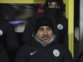 Manchester City manager Pep Guardiola awaits the start of the English League Cup semifinal soccer match between Burton Albion and Manchester City at Pirelli Stadium in Burton on Trent, England, Wednesday, Jan. 23, 2019.