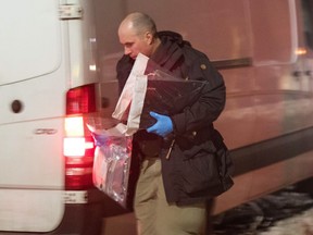 Police officer carry evidence from a house that police raided and arrested two police in Kingston, Ontario, on Thursday Jan. 24, 2019.