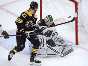 Boston Bruins center Danton Heinen (43) tips the puck past Minnesota Wild goaltender Alex Stalock, right, for a goal during the first period of an NHL hockey game in Boston, Tuesday, Jan. 8, 2019.