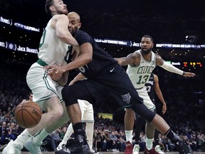 Minnesota Timberwolves forward Taj Gibson, center, collides with Boston Celtics forward Gordon Hayward, left, during the first quarter of an NBA basketball game in Boston, Wednesday, Jan. 2, 2019. At rear right is Celtics forward Marcus Morris (13).