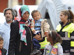 FILE- In this Sept. 8, 2015 file photo a woman and a child, along with other migrants and refugees, are transferred to a train bound for another German city, shortly after their arrival in Munich. Germany says that for the first time it has transferred more asylum seekers to other European Union countries than it took in from other EU countries.