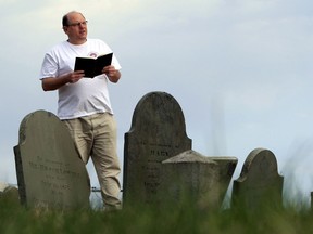 FILE - In this April 20, 2010 file photo, Walter Skold of Freeport, Maine, reads a Henry Wadsworth Longfellow poem while posing in Eastern Cemetery in Portland, Maine. Skold, the late founder of the Dead Poets Society of America, can be inducted to the society of fallen bards now that he's a published poet. Skold visited the gravesites of more than 600 poets and one of his criteria was that the subjects had to be published. Thanks to two of his children Charles and his brother Simon, he's becoming a published poet in 2019, posthumously, with his poetry book: "The Mirror is not Cracked."