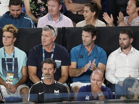 Serena Williams' coach, Patrick Mouratoglou, bottom left, sits in the player box of Greece's Stefanos Tsitsipas during his fourth round match against Switzerland's Roger Federer at the Australian Open tennis championships in Melbourne, Australia, Sunday, Jan. 20, 2019.