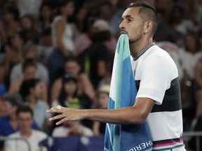 Australia's Nick Kyrgios walks with his towel in his mouth as he changes ends during his first round match against Canada's Milos Raonic at the Australian Open tennis championships in Melbourne, Australia, Tuesday, Jan. 15, 2019.