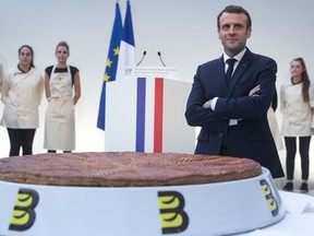 French President Emmanuel Macron poses next to a traditional epiphany cake at the Elysee Palace in Paris, France, Friday, Jan. 11, 2019.