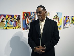 In this Thursday, Jan. 17, 2019 photo, Richard Phillips stands next to some of his artwork during an interview at the Community Art Gallery in Ferndale, Mich. Phillips was exonerated of murder in 2018 after 45 years in prison. Lawyers say he should be entitled to more than $2 million under Michigan's wrongful conviction law, but the state so far is resisting. So Phillips, 73, is selling some of his 400-plus watercolors that he painted in prison.