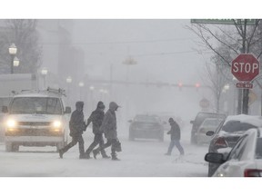 People walk through a snowstorm in downtown Jackson, Mich., Monday, Jan. 28, 2019.