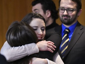 FILE - In this Feb. 5, 2018 file photo, Rachael Denhollander, center, hugs Det. Lt. Andrea Munford  in Eaton County Court in Charlotte, Mich., where ex-sports medicine doctor Larry Nassar was sentenced on three counts of sexual assault. Michigan State University's Board of Trustees will seek to oust interim President John Engler if he doesn't resign amid criticism of comments he has made about victims of Nassar, trustees said Wednesday, Jan. 16, 2019. Denhollander, a Nassar victim, told The AP Wednesday that her hope is that the board "is signaling at least the beginning of a true change in direction and tone.