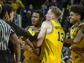 Michigan guard Charles Matthews, center, celebrates his game-winning buzzer-beater with forward Ignas Brazdeikis (13) and guard Jordan Poole, right, after an NCAA college basketball game against Minnesota at Crisler Center in Ann Arbor, Mich., Tuesday, Jan. 22, 2019. Michigan won 59-57.