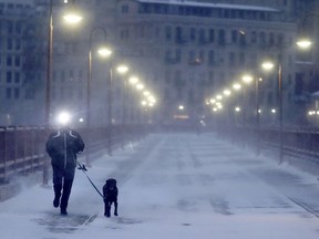 A runner and his dog brave frigid conditions while making their way east across the Stone Arch Bridge, Thursday, Jan. 24, 2019, in Minneapolis.   The National Weather Service issued a wind child advisory overnight Thursday for Wisconsin, Minnesota, the Dakotas and several other states.
