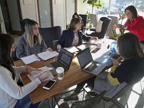 In this Jan. 16, 2019 photo, ModernWell founder Julie Burton, right, arranges flowers as four women confer on a non-profit event in Minneapolis. ModernWell is one of a growing number of women-only and women-focused workspaces around the country. While many predate the #MeToo movement, their growth has been interlinked with it as it put combating workplace harassment on the national agenda.