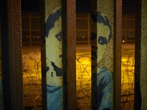 An image of a boy is painted on the bars of the border wall, in front of coils of razor wire Friday, Jan. 11, 2019, seen from Tijuana, Mexico. The partial government shutdown was on track Friday to become the longest closure in U.S. history as President Donald Trump and nervous Republicans looked for a way out of the mess. A solution couldn't come soon enough for federal workers who got pay statements Friday but no pay.