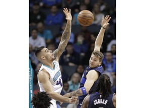 Dallas Mavericks' Luka Doncic, right, passes the ball as Charlotte Hornets' Willy Hernangomez, left, defends during the first half of an NBA basketball game in Charlotte, N.C., Wednesday, Jan. 2, 2019.