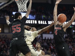 Wake Forest's Brandon Childress (0) is fouled as he drives between North Carolina State's Blake Harris (55) and Jericole Hellems (4) during the first half of an NCAA college basketball game in Winston-Salem, N.C., Tuesday, Jan. 15, 2019.