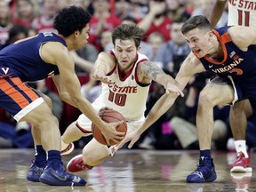 Virginia's Kihei Clark, left, and Kyle Guy reach for a loose ball with North Carolina State's Braxton Beverly (10) during the first half of an NCAA college basketball game in Raleigh, N.C., Tuesday, Jan. 29, 2019.